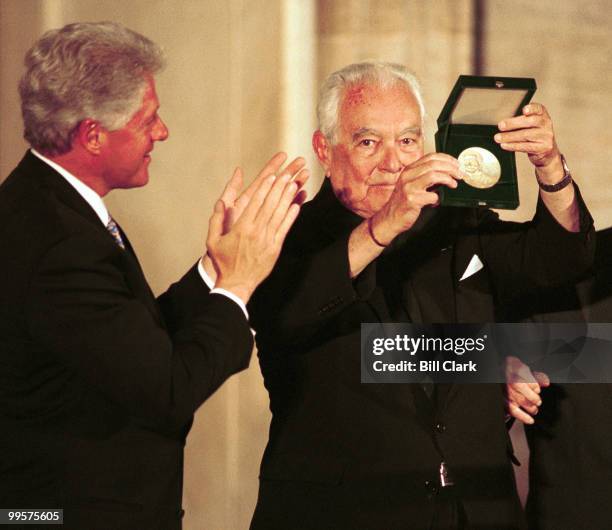 Pres. Bill Clinton claps as Rev. Theodore Hesburgh shows his Congressional Gold Medal.
