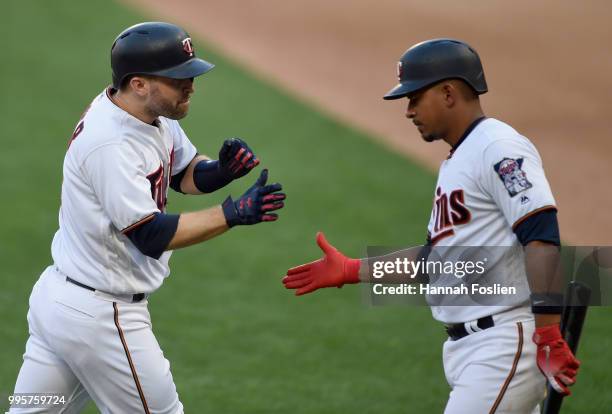 Eduardo Escobar of the Minnesota Twins congratulates teammate Brian Dozier on a solo home run against the Kansas City Royals during the first inning...