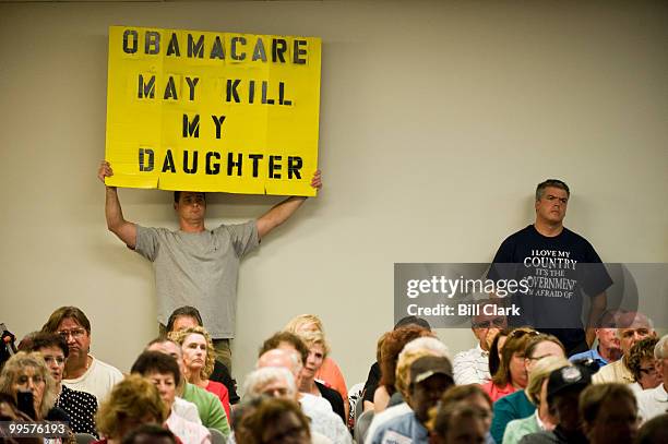 Michael Craig, left, of Middletown, N.J., holds up a sign opposing Obamacare during Rep. Frank Pallone's town hall meeting at Red Bank Middle School...