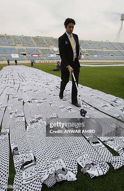 Guiness World Records representative Jack Brockbank measures the length of the world's largest keffiyeh, the traditional black-and-white chequerred...