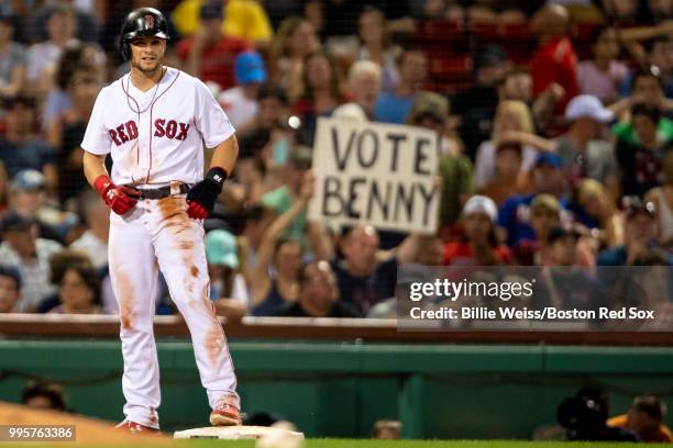 Sign holds a fan as Andrew Benintendi of the Boston Red Sox reacts after stealing third base during the seventh inning of a game against the Texas...