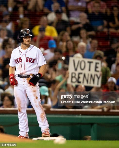 Sign holds a fan as Andrew Benintendi of the Boston Red Sox reacts after stealing third base during the seventh inning of a game against the Texas...