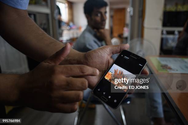 In a photo taken on July 4 Yemeni asylum seeker Mohammed Salem Duhaish shows an image of a bomb blast in the Yemeni capital of Sana'a on his mobile...