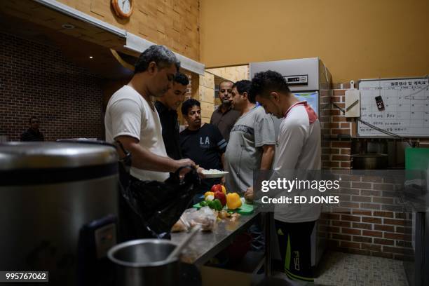 In a photo taken on July 4 Yemeni asylum seekers prepare lunch at the Olle Tourist Hotel in Jeju. - A few hundred asylum-seekers from Yemen have...