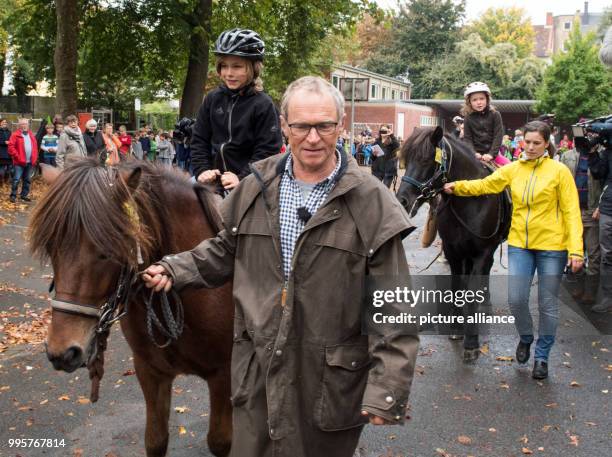 Wandering rider Hans Watzl and his grandchildren Hannes abnd Esther can be seen on the backs of two horses riding home from school in Muenster,...