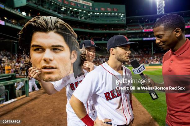 Brock Holt of the Boston Red Sox holds up a big-head cutout of Andrew Benintendi as he is interview by Jahmai Webster of NESN after a game against...