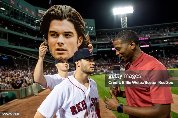 Brock Holt of the Boston Red Sox holds up a big-head cutout of Andrew Benintendi as he is interview by Jahmai Webster of NESN after a game against...