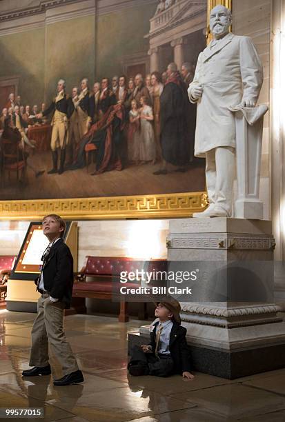 From left, Jack Boekeloo looks up at the Capitol Rotunda as his brother Will sits at the base of the James Garfield statue while on a tour of the...