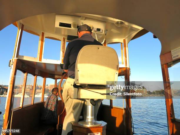 rear view of pilot guiding victora water taxi toward empress hotel, victoria inner harbour - victoria harbour vancouver island stock pictures, royalty-free photos & images