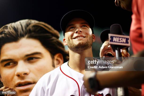 Brock Holt of the Boston Red Sox holds up a cut out of the face of Andrew Benintendi of the Boston Red Sox as Benintendi is interviewed by NESN...