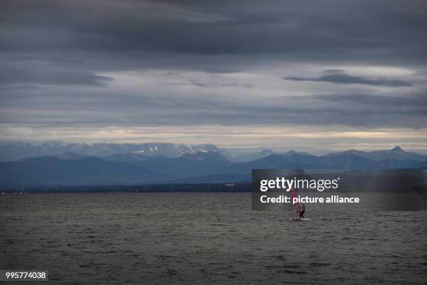 Sail boarder can be seen in front of the alpine panorama under neath thick clouds on the Ammer Lake near Inning, Germany, 02 October 2017. Photo:...