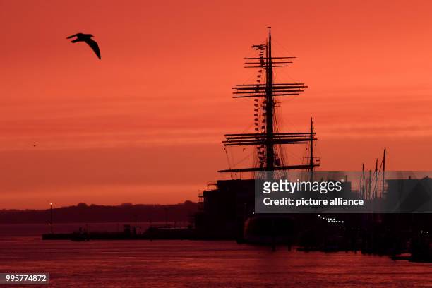 Dpatop - The sky appears red during sunrise above the 4 mast passat ship in Travemuende, Germany, 03 October 2017. Photo: Maurizio Gambarini/dpa