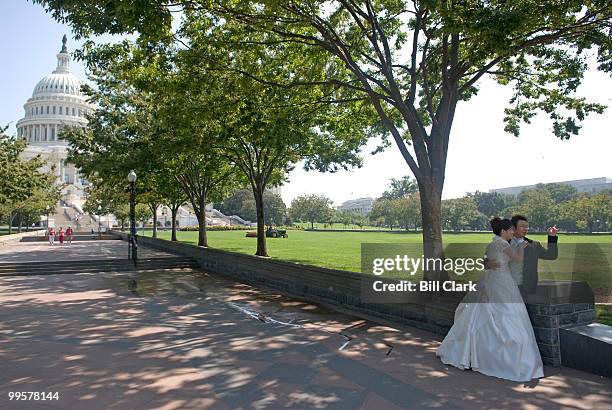 Sunny Kim, left, and John Choi, both of Centerville, Va., pose for their wedding photos along the west lawn of the Capitol on Monday afternoon, Sept....