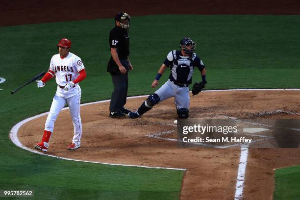 Shohei Ohtani of the Los Angeles Angels of Anaheim reacts to a called strike by umpire D.J. Reyburn as Chris Herrmann of the Seattle Mariners looks...