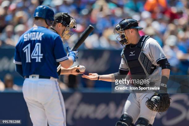 Toronto Blue Jays First baseman Justin Smoak gets ready to bat as New York Yankees Catcher Austin Romine gets handed a fresh ball by MLB Home Plate...