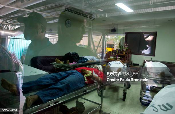 The glass reflects people at Rama Hospital as a Red shirt protesters lays dead inside the morgue as the violence in central part of the city...