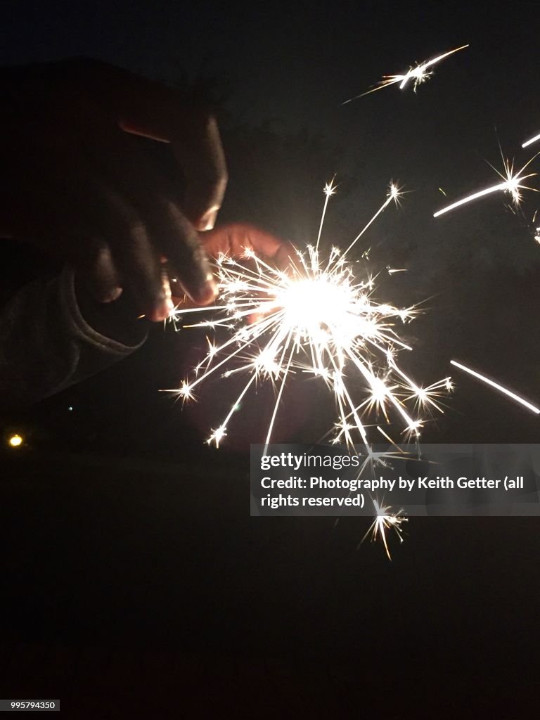 Youngsters playing with sparklers to celebrate July 4th USA Independence Day holiday