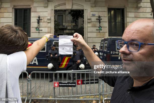 Catalan pro-independence activists hold up referendum ballots in front of a Spanish government building as they participate in a mass demonstration...