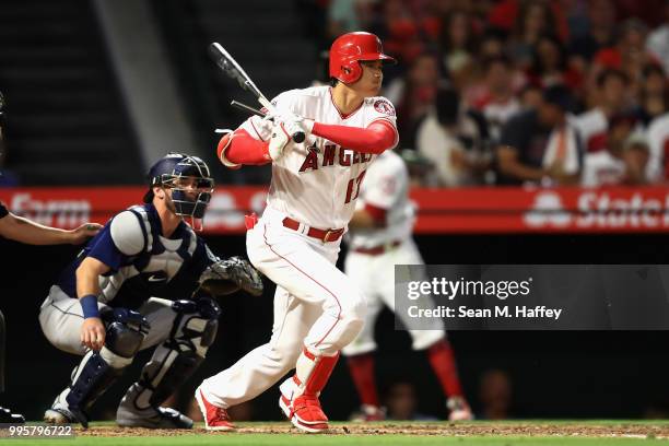 Shohei Ohtani of the Los Angeles Angels of Anaheim grounds out as Chris Herrmann of the Seattle Mariners looks on during the third inning of a game...