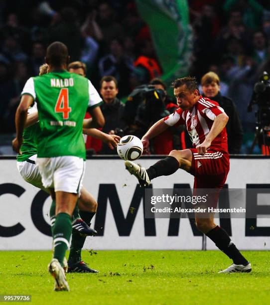 Per Mertesacker of Bremen plays handball ahead of Ivica Olic of Bayern during the DFB Cup final match between SV Werder Bremen and FC Bayern Muenchen...