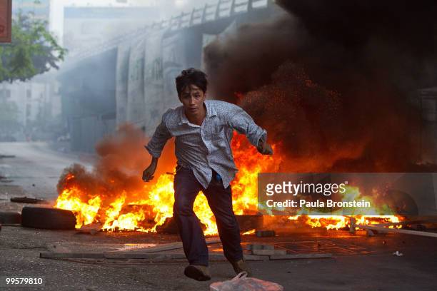 Red shirt protester runs away from the gunfire as the violence in central part of the city escalates on May 15, 2010 in Bangkok, Thailand. So far at...