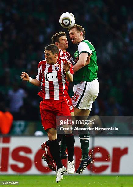 Bastian Schweinsteiger and Thomas Mueller of Bayern jump for header with Per Mertesacker of Bremen during the DFB Cup final match between SV Werder...