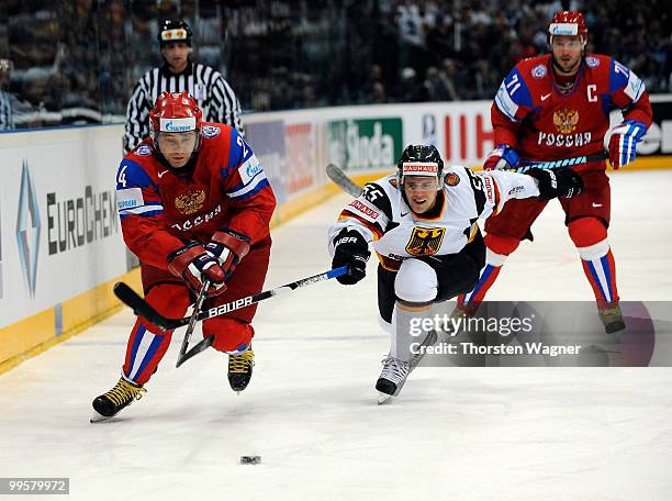 Felix Schultz of Germany battles for the puck with Alexander Frolov of Russia during the IIHF World Championship qualification round match between...