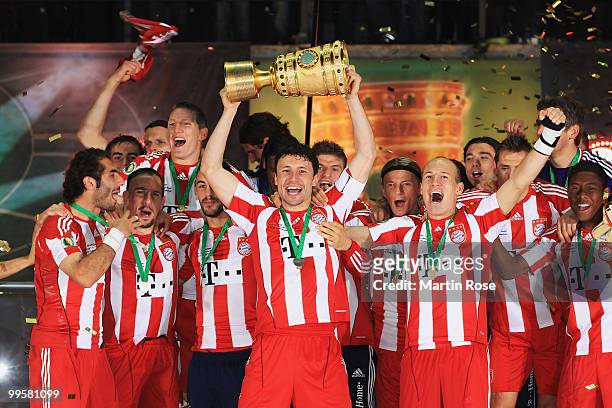 Mark van Bommel of Bayern Muenchen lifts the DFB Cup trophy following his team's victory at the end of the the DFB Cup final match between SV Werder...