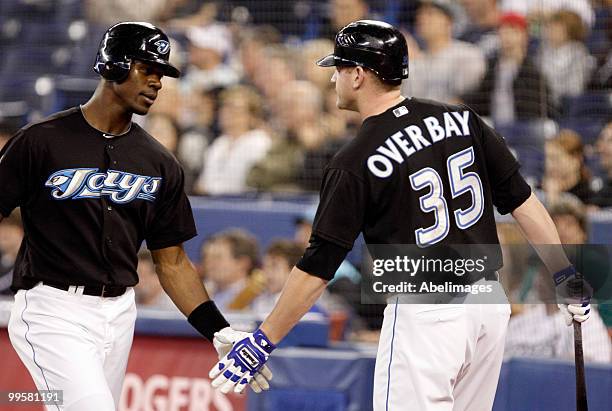 Fred Lewis and Lyle Overbay of the Toronto Blue Jays celebrate an Adam Lind RBI against the Texas Rangers during a MLB game at the Rogers Centre May...