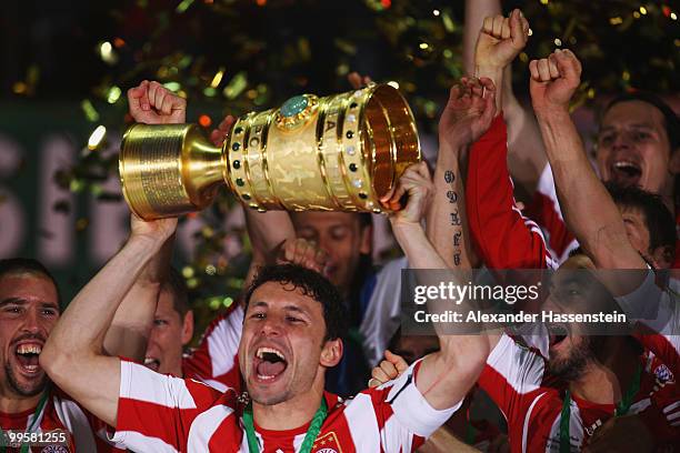 Mark van Bommel of Bayern Muenchen lifts the DFB Cup trophy following his team's victory at the end of the DFB Cup final match between SV Werder...