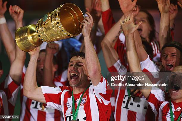 Mark van Bommel of Bayern Muenchen lifts the DFB Cup trophy following his team's victory at the end of the DFB Cup final match between SV Werder...