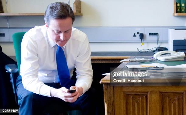In this handout image provided by the Conservative Party ,Leader of the Conservative Party David Cameron texts on his mobile phone as he waits for...