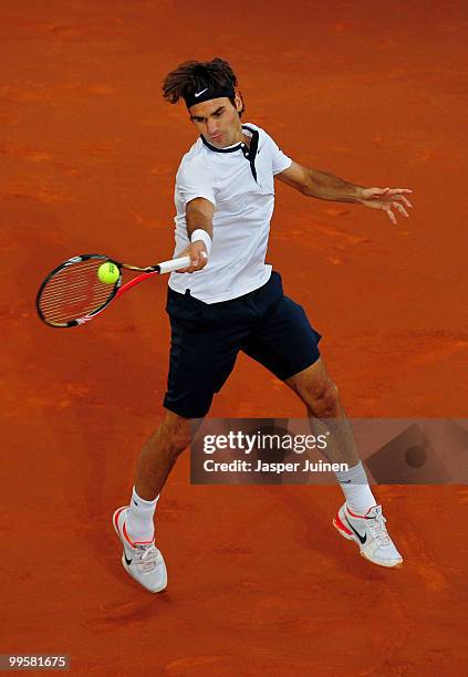 Roger Federer of Switzerland jumps to play a backhand to David Ferrer of Spain in their semi-final match during the Mutua Madrilena Madrid Open...