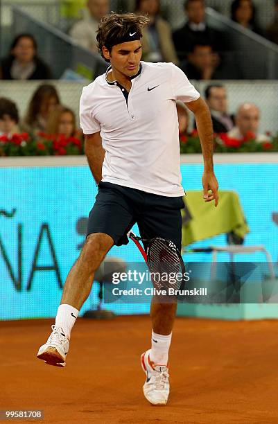 Roger Federer of Switzerland jumps to play a shot through his legs against David Ferrer of Spain in their semi final match during the Mutua Madrilena...