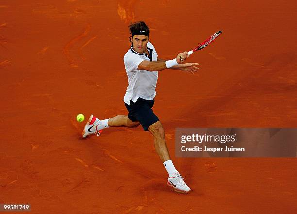 Roger Federer of Switzerland slides to play a backhand to David Ferrer of Spain in their semi-final match during the Mutua Madrilena Madrid Open...