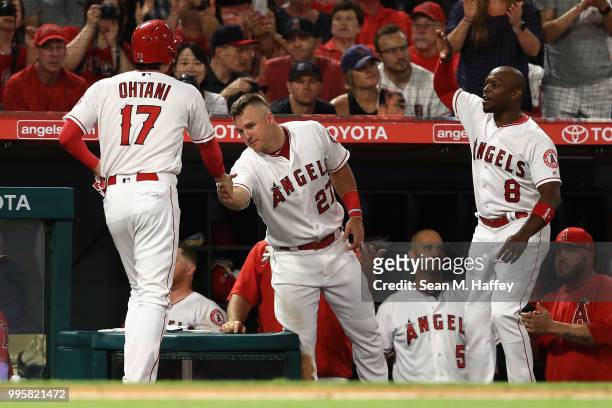 Shohei Ohtani is congratulated by Mike Trout and Justin Upton after scoring on a single by Ian Kinsler of the Los Angeles Angels of Anaheim during...