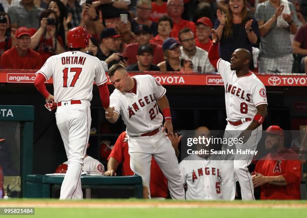 Shohei Ohtani is congratulated by Mike Trout and Justin Upton after scoring on a single by Ian Kinsler of the Los Angeles Angels of Anaheim during...