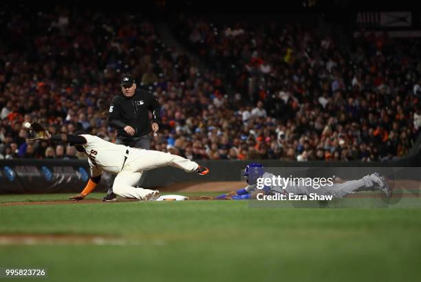 Addison Russell of the Chicago Cubs slides safely in to third base as Pablo Sandoval of the San Francisco Giants dives for a wild throw from catcher...