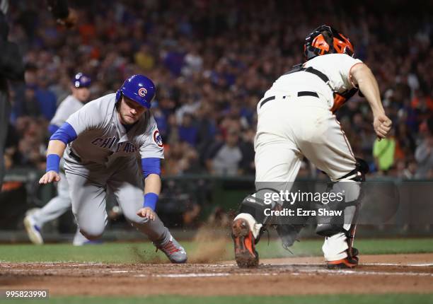 Ian Happ of the Chicago Cubs slides safely past Nick Hundley of the San Francisco Giants to score on a hit by Victor Caratini of the Chicago Cubs in...
