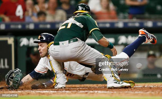 Josh Reddick of the Houston Astros scores in the eleventh inning as Jonathan Lucroy of the Oakland Athletics can't handle the throw on a fielder's...