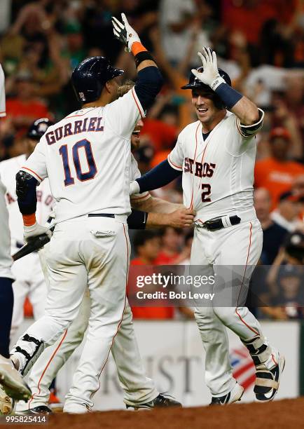 Alex Bregman of the Houston Astros celebrates with Yuli Gurriel after scoring in the eleventh inning to beat the Oakland Athletics at Minute Maid...