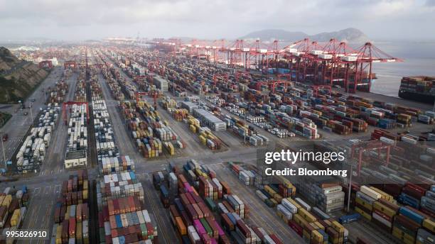 Containers sit stacked next to gantry cranes at the Yangshan Deep Water Port in this aerial photograph taken in Shanghai, China, on Tuesday, July 10,...