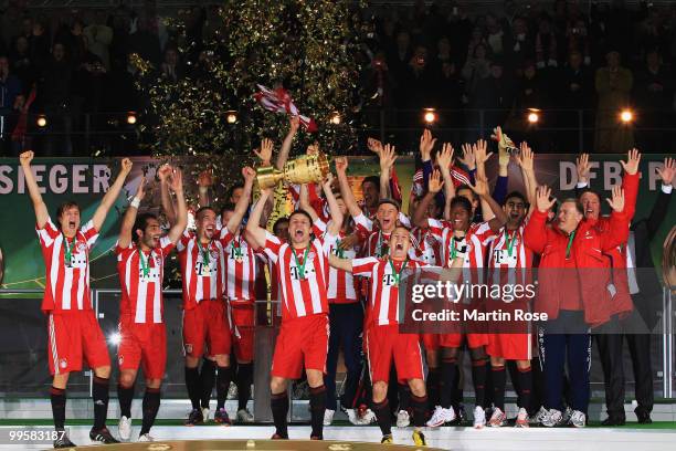 Bayern Muenchen players celebrate with the DFB Cup trophy following their victory at the end of the DFB Cup final match between SV Werder Bremen and...