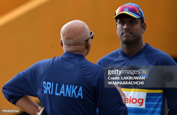 Sri Lankan cricketer Angelo Mathews talks with coach Chandika Hathurusingha during a training session at the Galle International Cricket Stadium in...