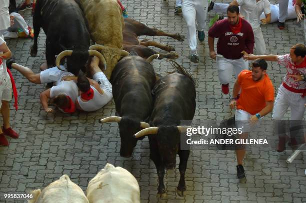 Participants fall with Nunez del Cuvillo fighting bulls on the fifth bullrun of the San Fermin festival in Pamplona, northern Spain on July 11, 2018....