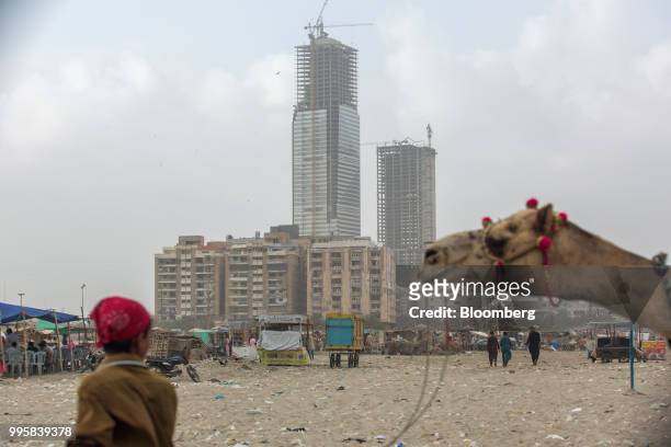 Boy leads a camel as buildings stand under construction at Clifton Beach in Karachi, Pakistan, on Monday, July 9, 2018. The Pakistan economy is in...