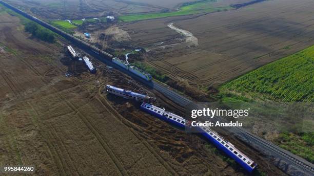An aerial view of a passenger train on the repaired railway passing five derailed carriages, which await removal, after the accident at the Sarilar...