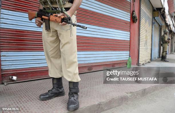 Indian paramilitary troopers stand guard in front of closed shops in Srinagar on July 11, 2018. - Kashmiri seperatists have called a one-day strike...