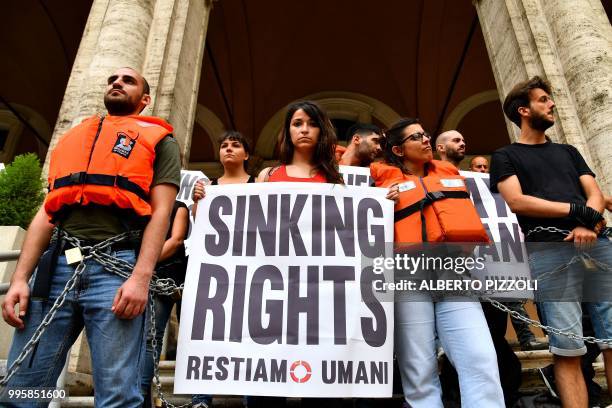 "We remain human" network activists hold banners reading "Sinking rights" as they are chained on the steps of the Ministry of Transport to protest...