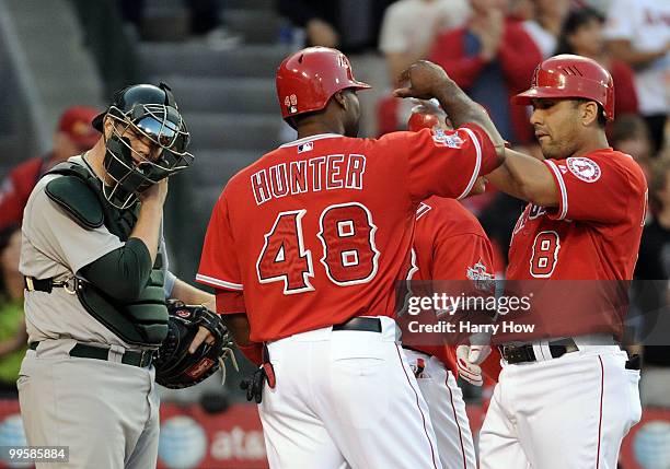 Landon Powell of the Oakland Athletics reacts as Kendry Morales and Torii Hunter of the Los Angeles Angels celebrate a three run homerun during the...
